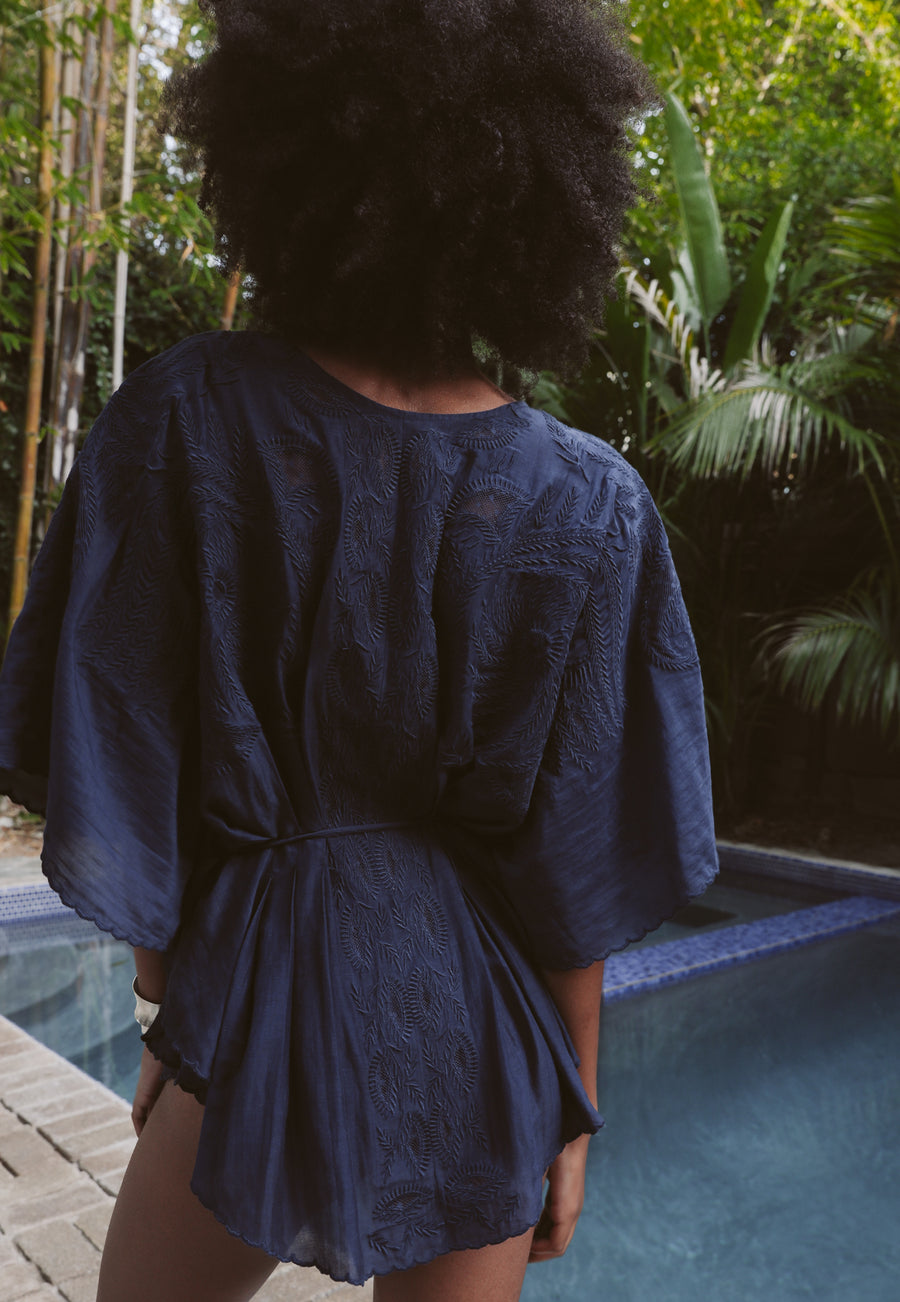 Indigo embroidered cape/cover up lays over shoulders with ties at neck and waist.  Darted back creates defining back peplum with a vintage flair. 