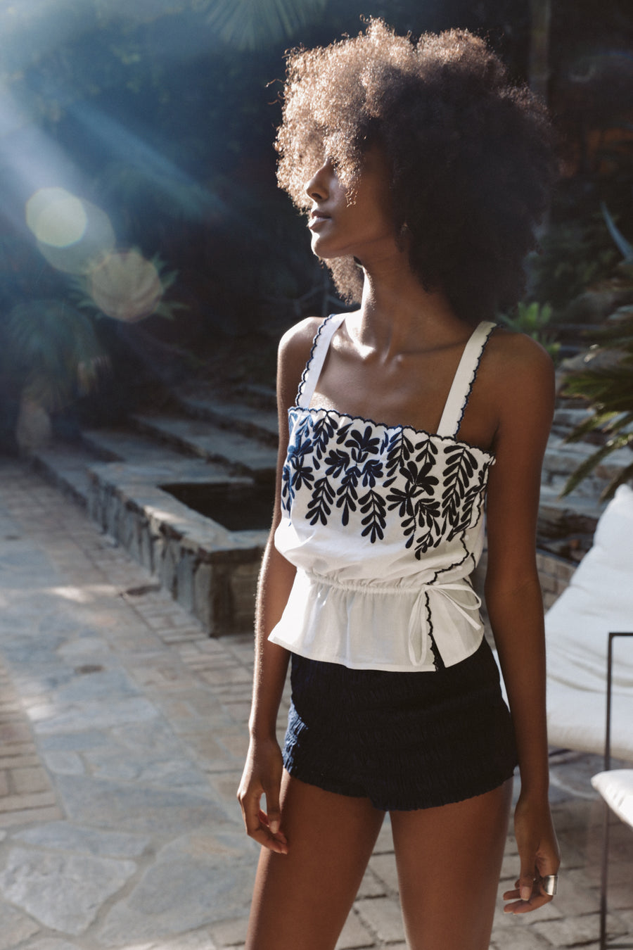 Lightweight 100% pima cotton camisole in white with indigo blue embroidered petals, delicate side covered buttons, and an adjustable drawstring waist.